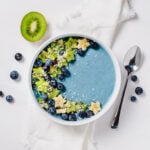 Blue smoothie bowl with stars cut from kiwi and banana and blueberries.