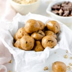 Vegan chocolate chip cookie dough balls in bowl next to bowls with oats and chocolate chips