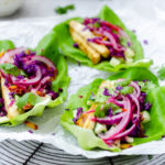 Lettuce wraps filled with tofu, lime-pickled onion, cabbage and cucumber garnished with cilantro
