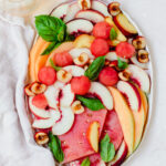 Fruit plate with yellow and white peaches, cantaloupe, watermelon and cherries.