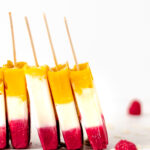 A popsicle with mango, coconut and raspberry layers.