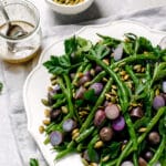 Plate of green beans with purple potatoes and pumpkin seeds with a