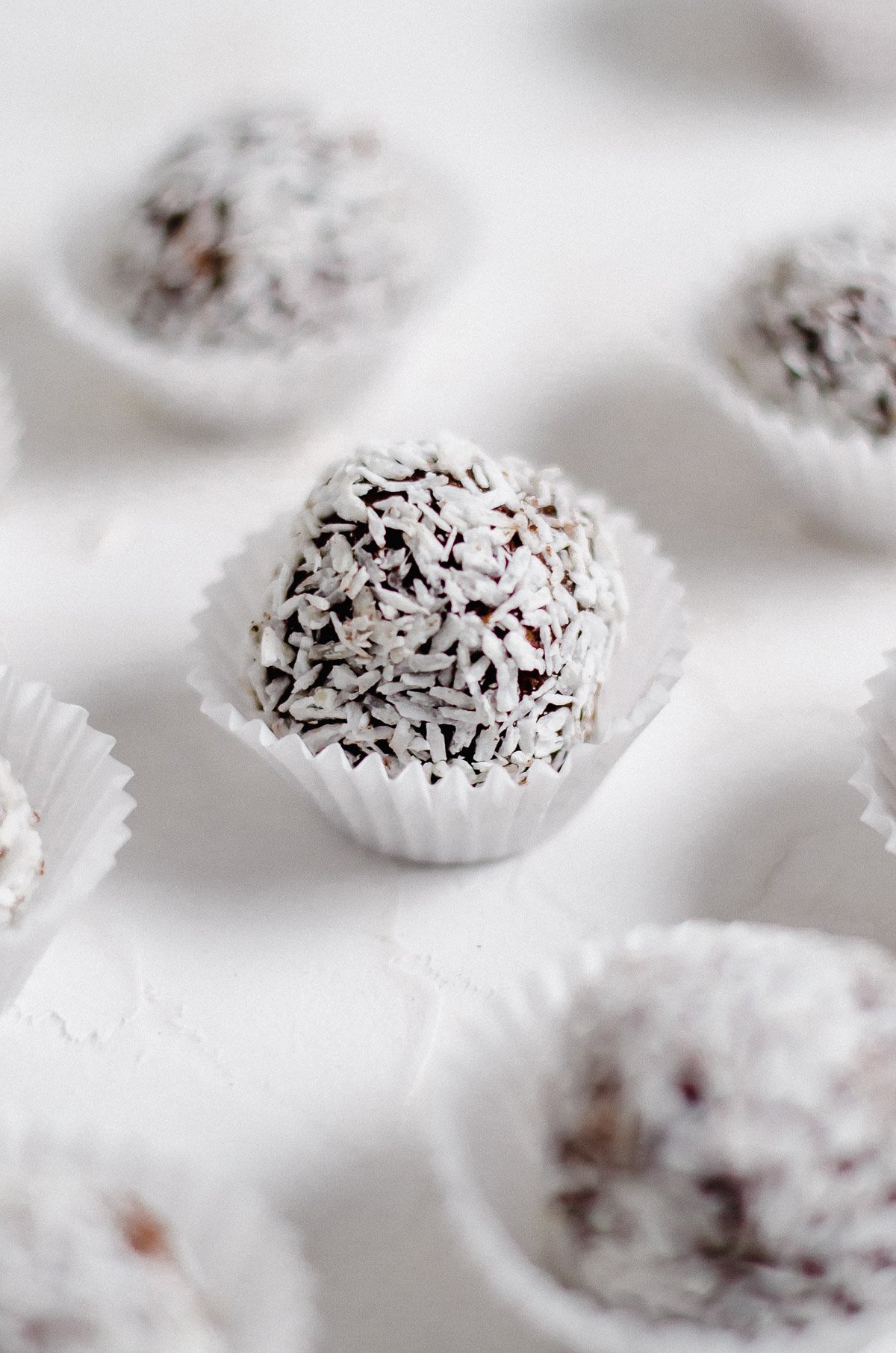 Close up photo of a vegan dark chocolate truffle coated with coconut flakes in a wrapper