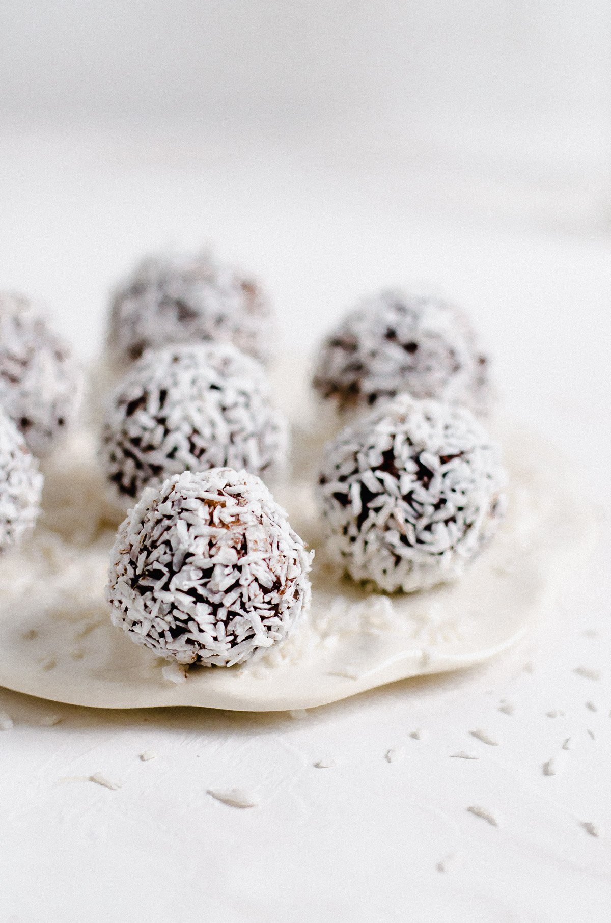 Plate of vegan dark chocolate truffles covered with coconut flakes.