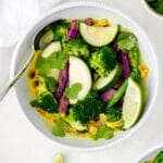 Bowl of warming yellow coconut curry sauce with zucchini, broccoli, string beans, sweet potatoes.