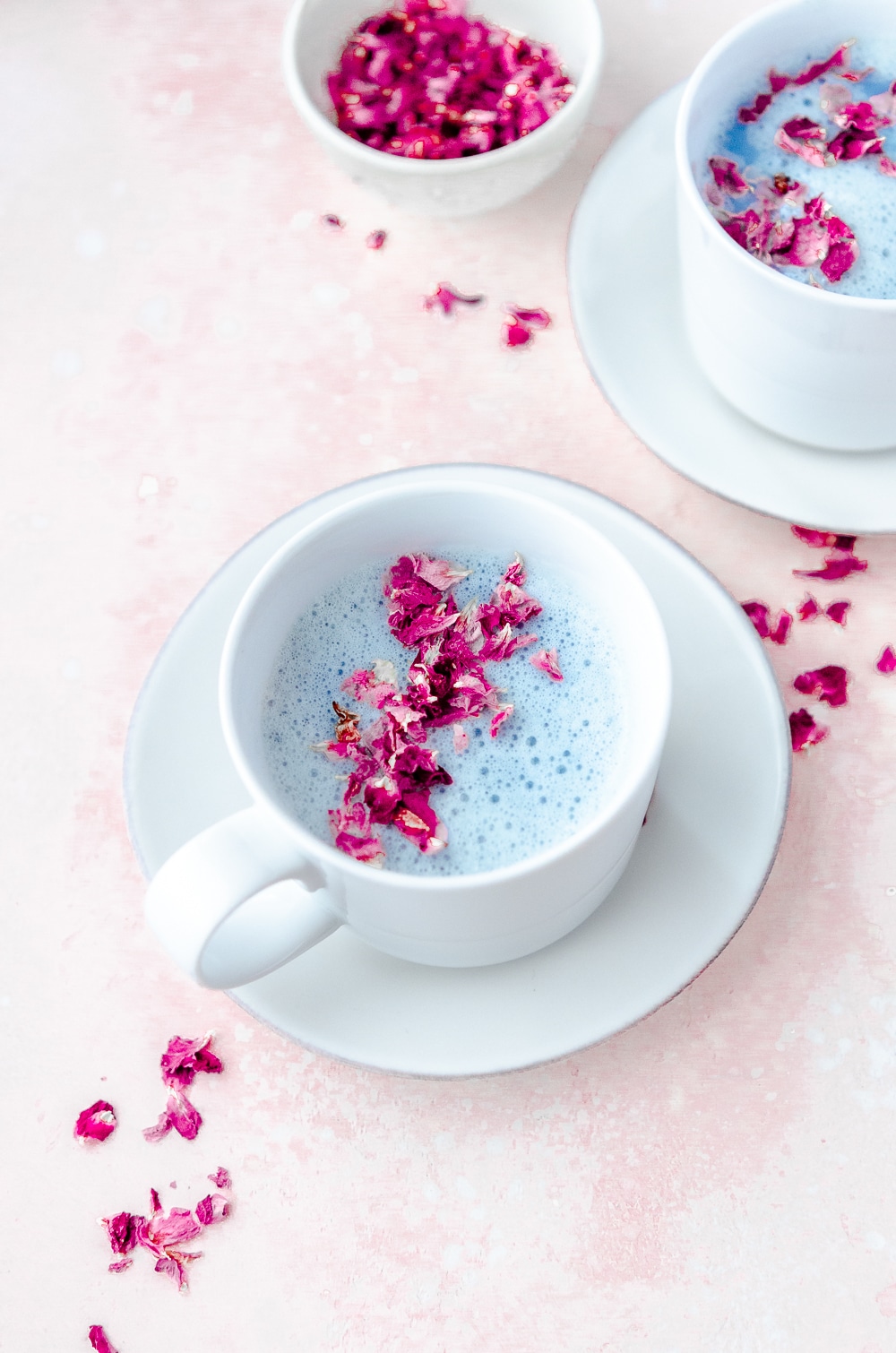 Cup of blue lavender moon milk with blue spirulina and ashwagandha. Decorated with dried rose petals.