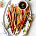 Platter of rainbow carrots roasted with honey, miso, tamari and garnished with sesame seeds.