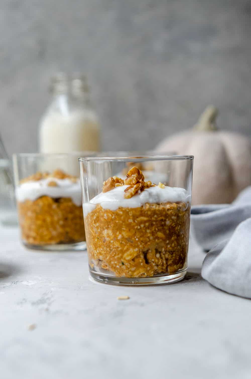 Glass of pumpkin spice overnight oats topped with coconut yogurt and walnuts