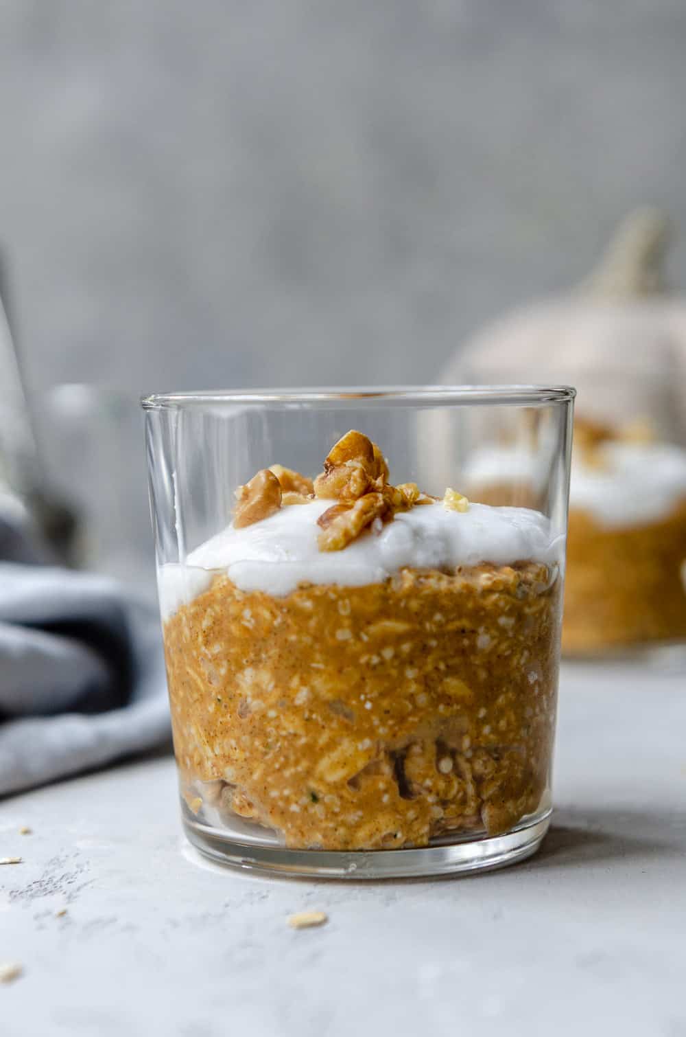 Glass of pumpkin spice overnight oats topped with coconut yogurt and walnuts