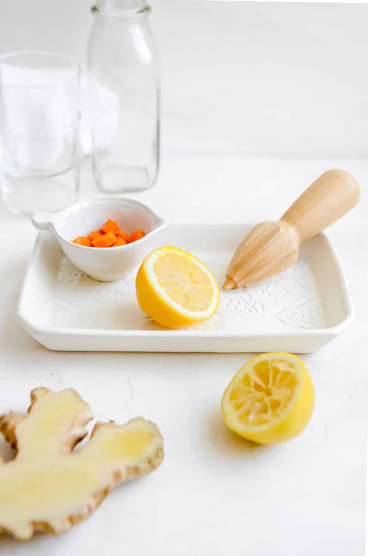 Ingredients to make a turmeric ginger smoothie including lemons, sliced ginger and turmeric on a decorative tray.