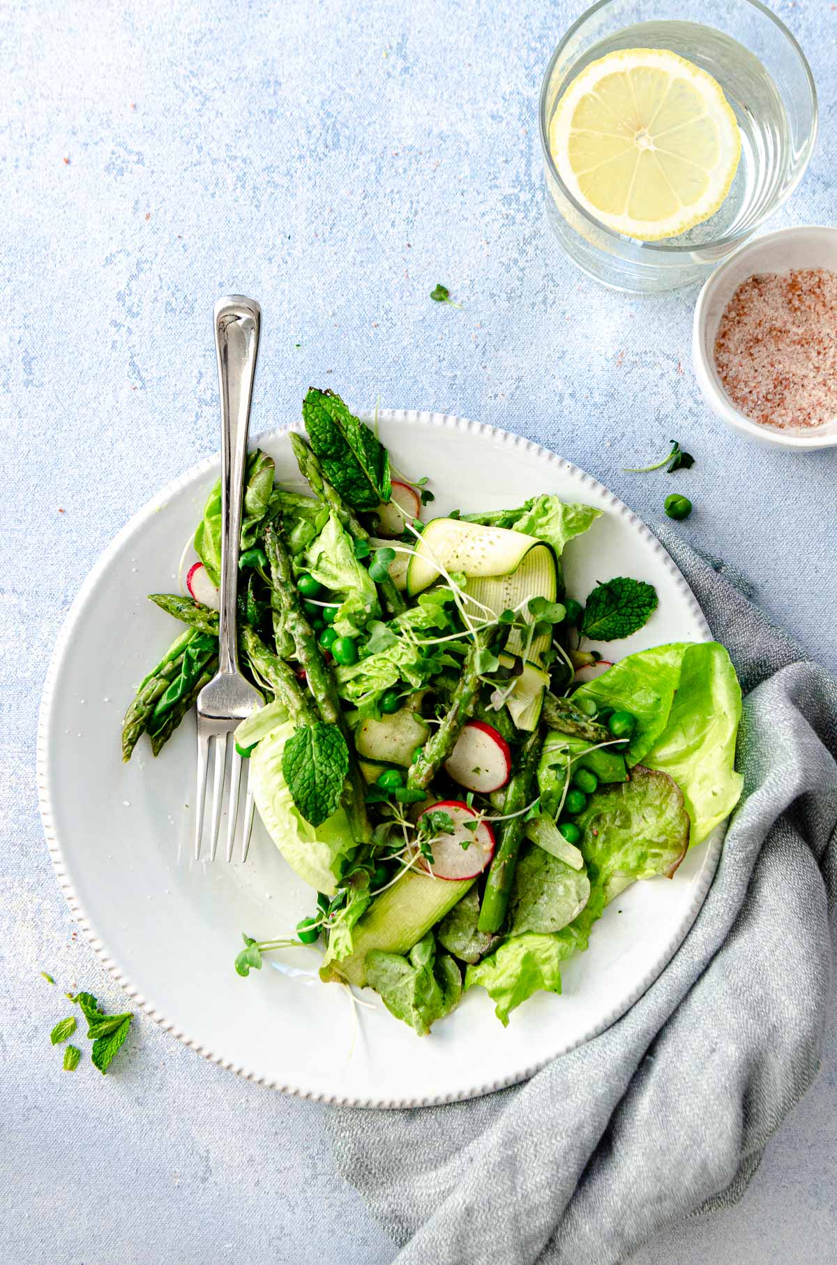 Plate of a mixed spring green goddess salad with asparagus, peas, butter lettuce, mint, radishes, broccoli micro greens