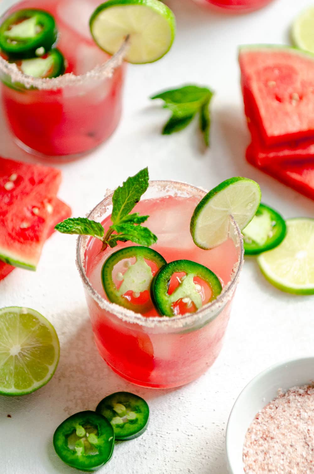 Watermelon margarita with pink salt rim and garnished with jalapeño, mint and watermelon slices