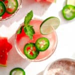 Skinny spicy watermelon margarita with pink salt rim and garnished with jalapeño, mint and watermelon slices