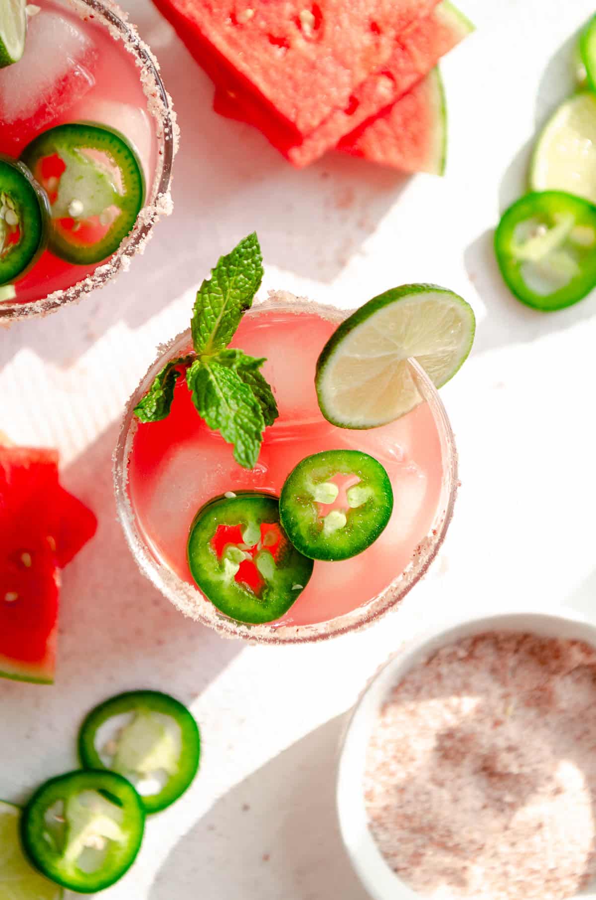 Skinny spicy watermelon margarita with pink salt rim and garnished with jalapeño, mint and watermelon slices