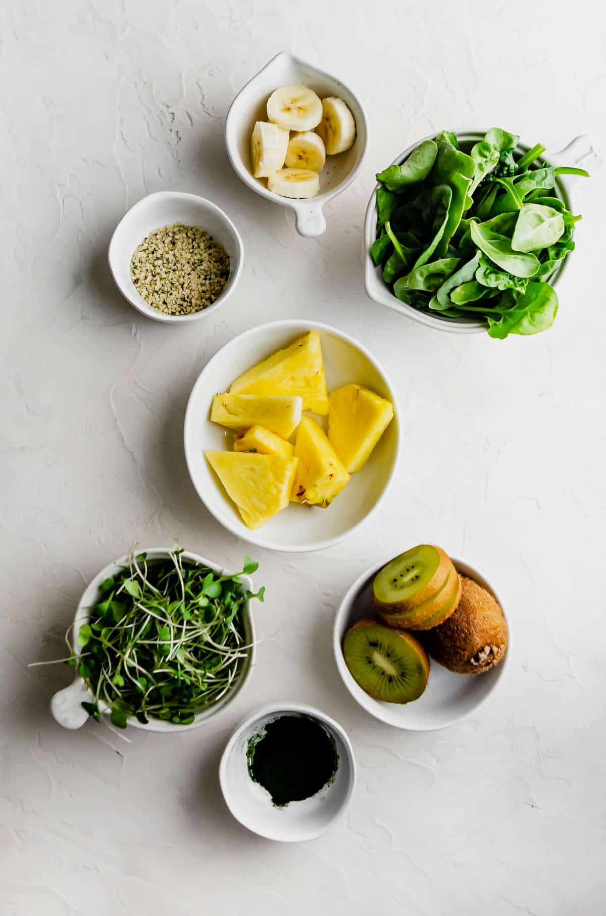 Ingredients for Super Green Smoothie including microgreens, baby spinach, kiwi, banana, hemp seed, spiraling