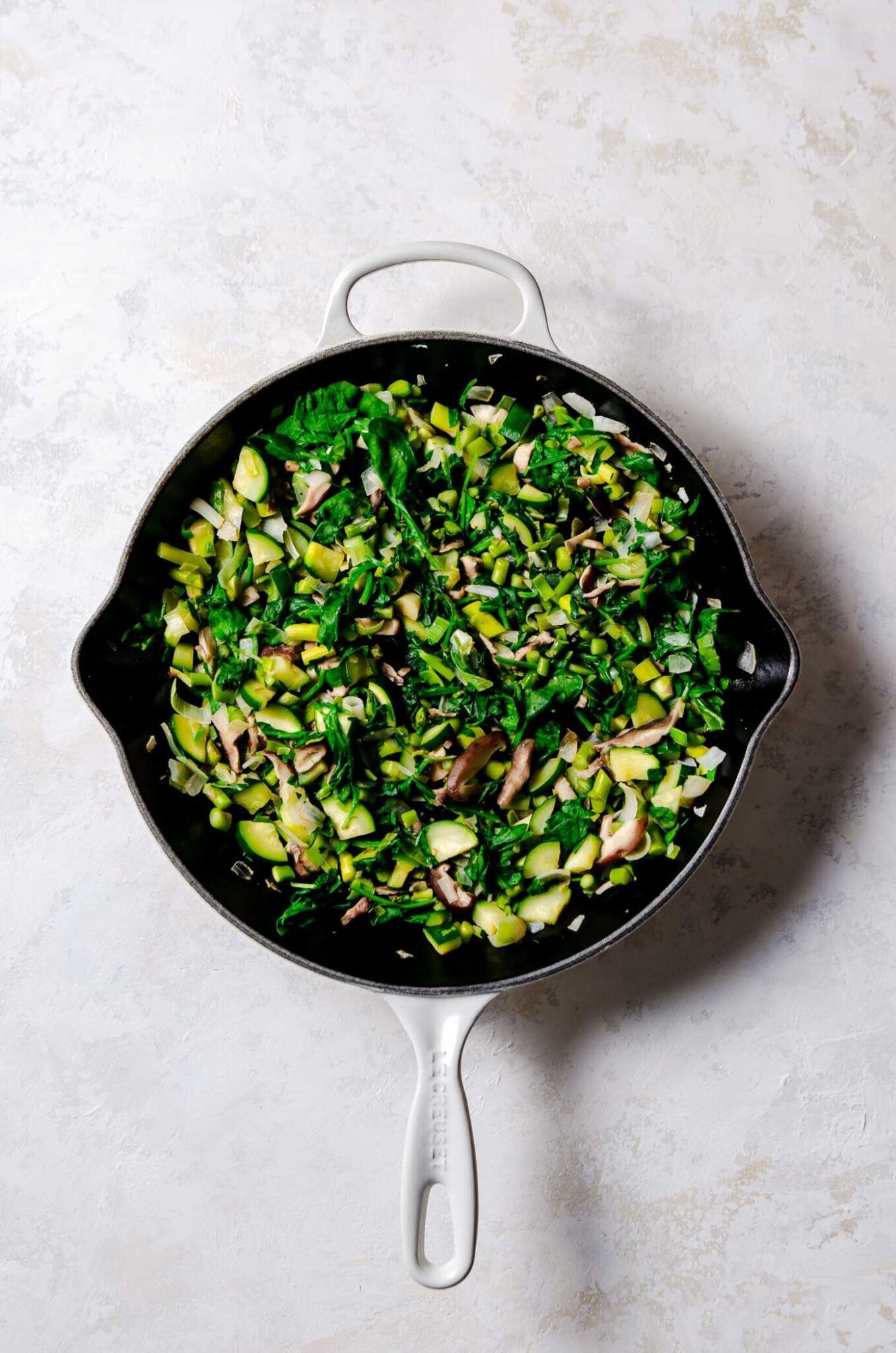 Sautéed mixture of zucchini, baby spinach, leeks, onions, shiitake mushrooms in a cast iron pan. 