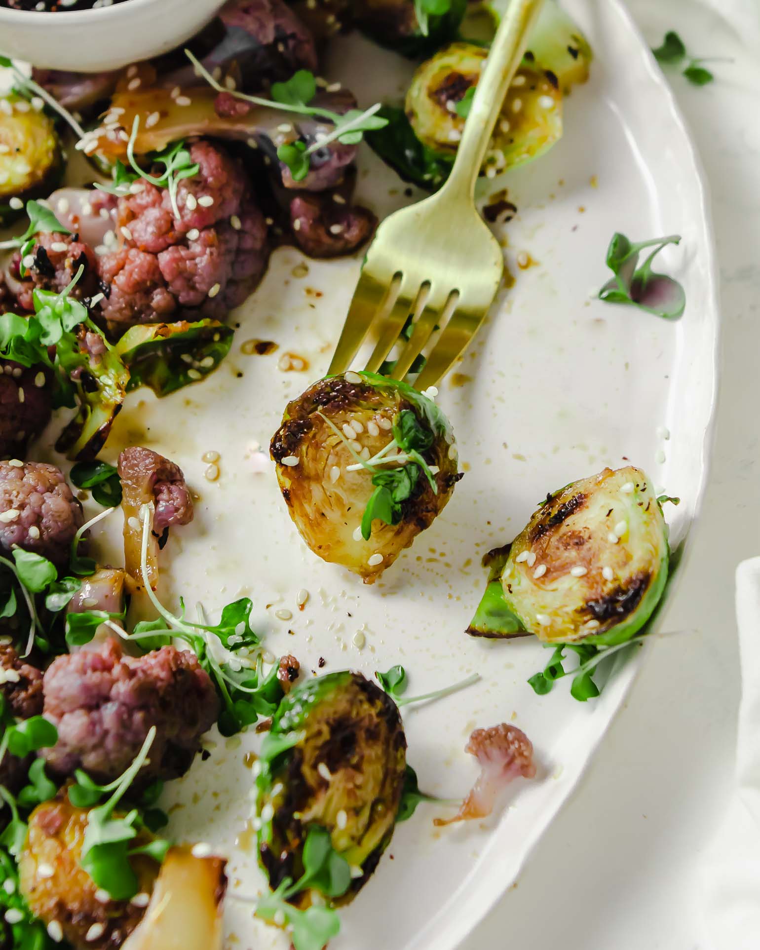 Close up of honey soy brussels sprouts with a sprout on a fork.