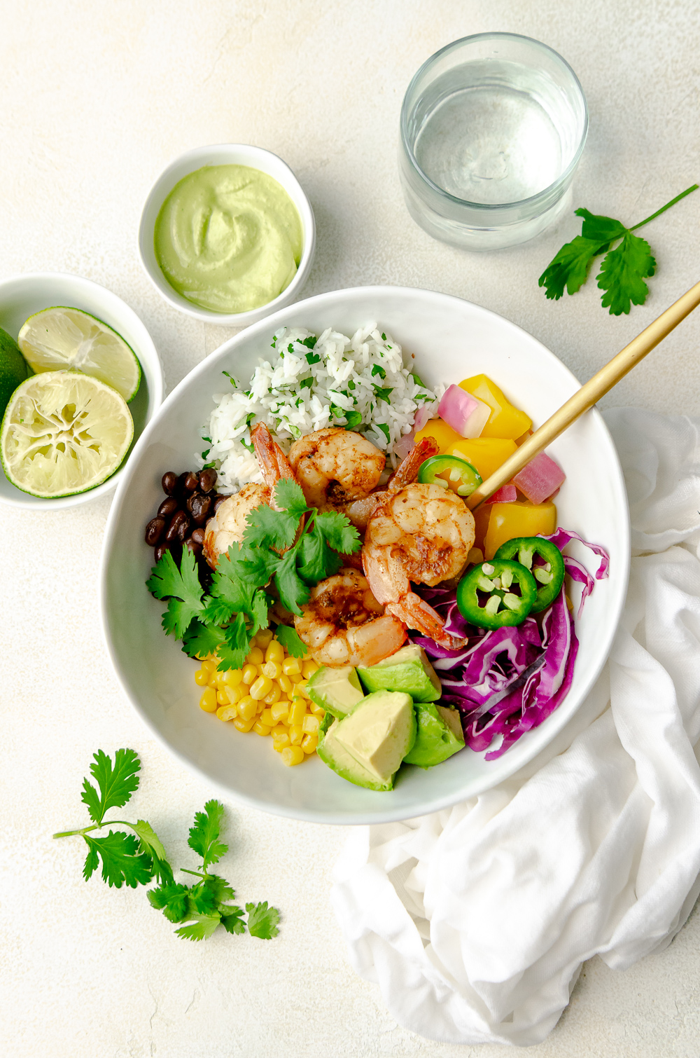 Burrito Bowl made with pink shrimp, white rice, black beans and garnished with yellow peppers, red cabbage, avocado, corn and cilantro. 