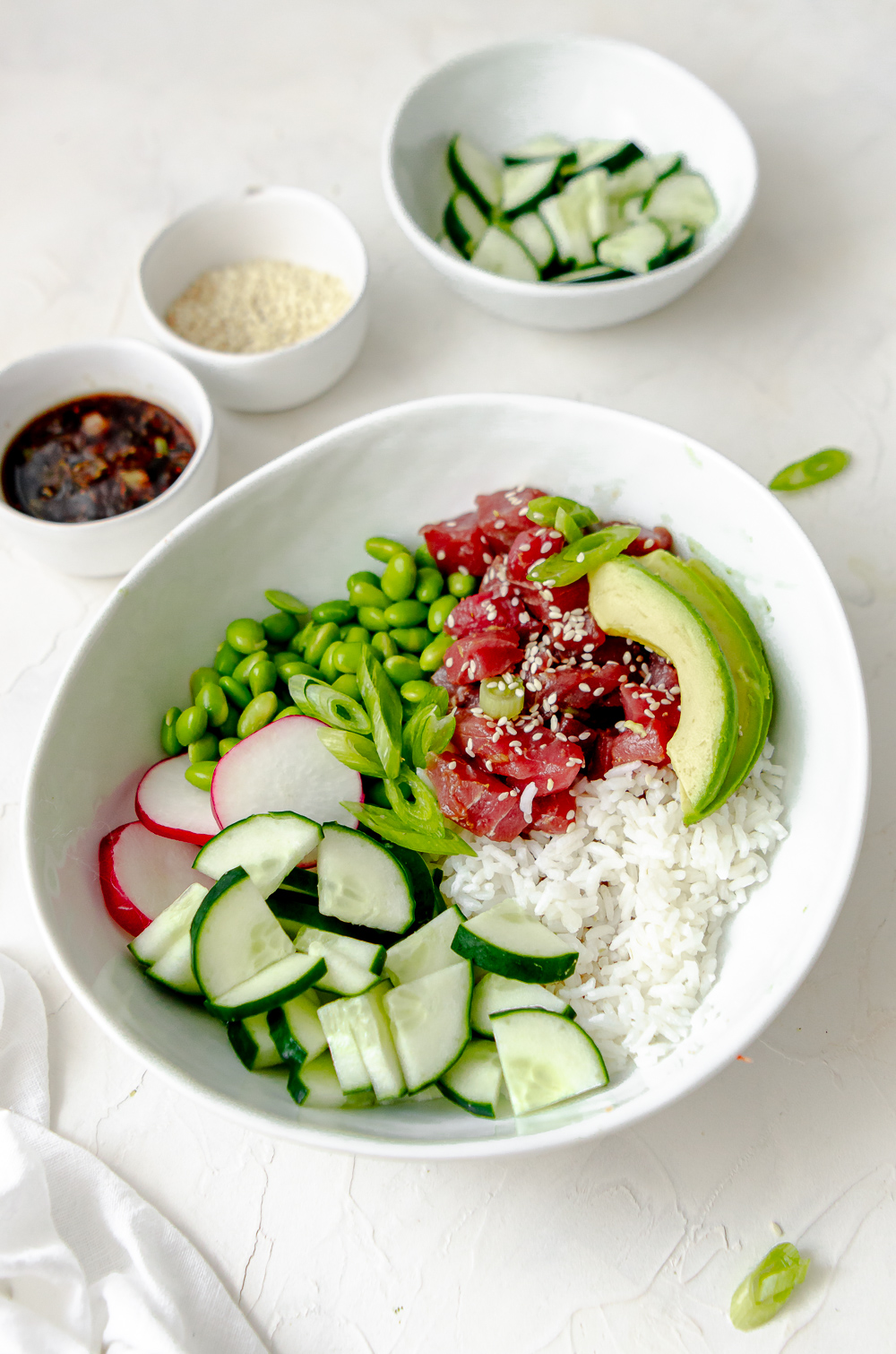 Marinated tuna poke bowl made with edamame, avocado, white rice, cucumbers and radish. 