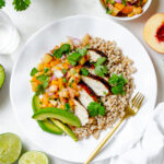 This peach salsa chicken combines fragrant peaches, crunchy bell peppers, cilantro, lime juice and a barbecue-spiced grilled chicken. Served on a dish with farro.