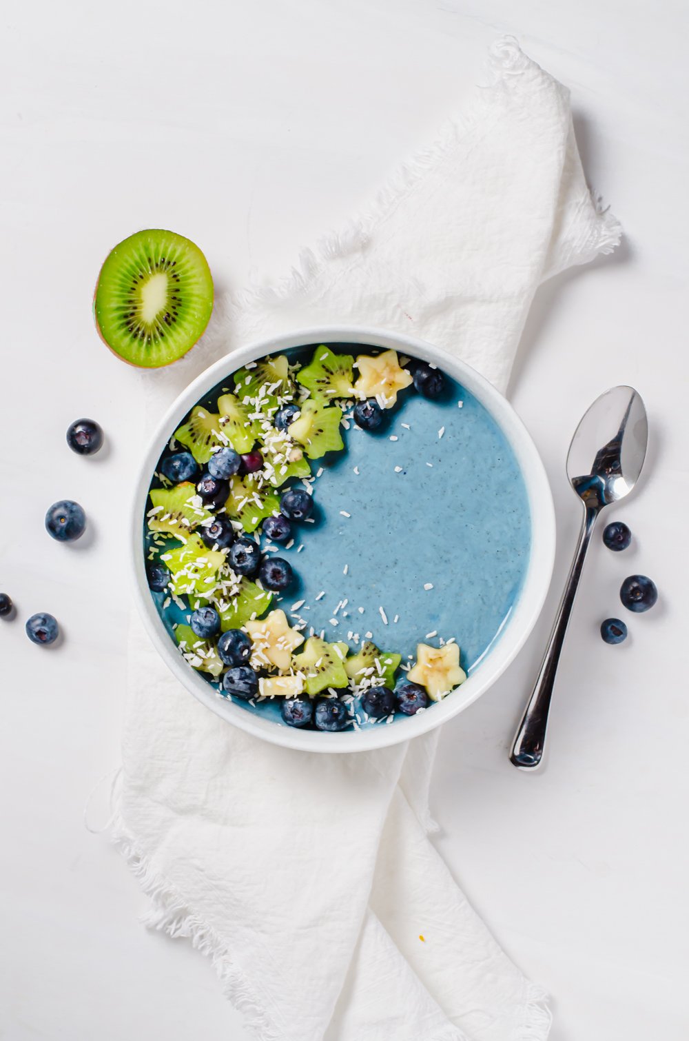 A blue smoothie bowl made with Blue Majik spirulina and topped with kiwis, blueberries, bananas and coconut flakes.