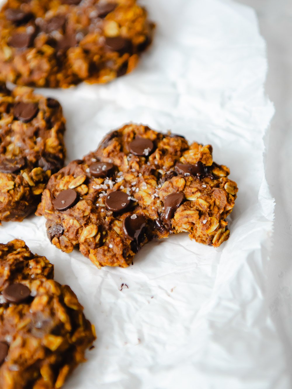 Close up of a healthy pumpkin oatmeal cookie with a small bite taken out of it. 