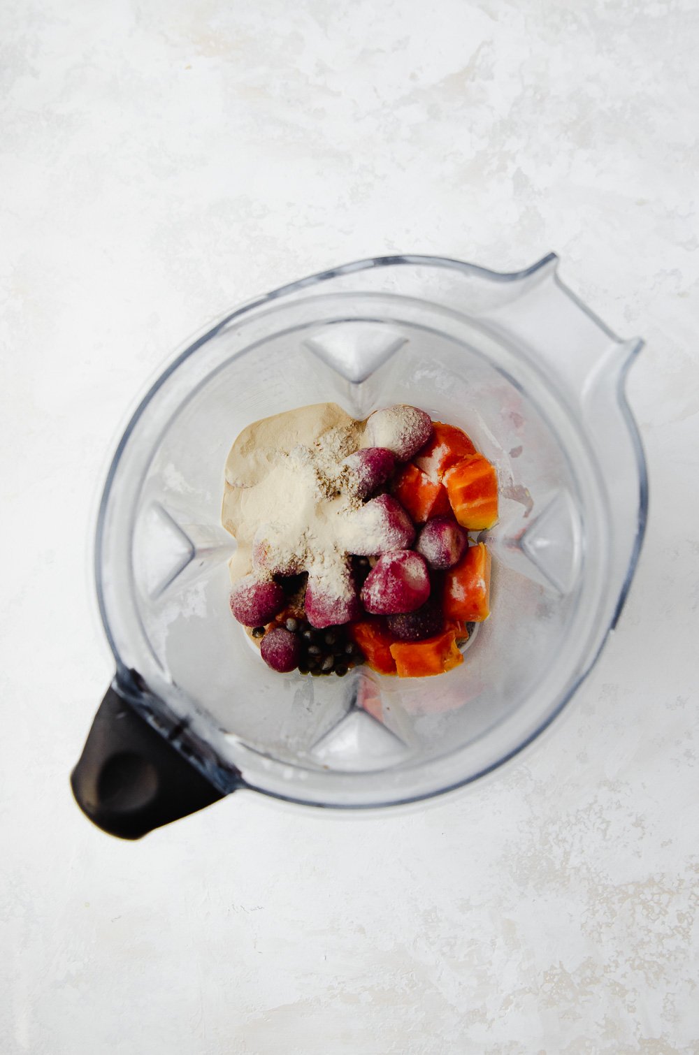 Ingredients for a strawberry papaya protein smoothie in a blender.