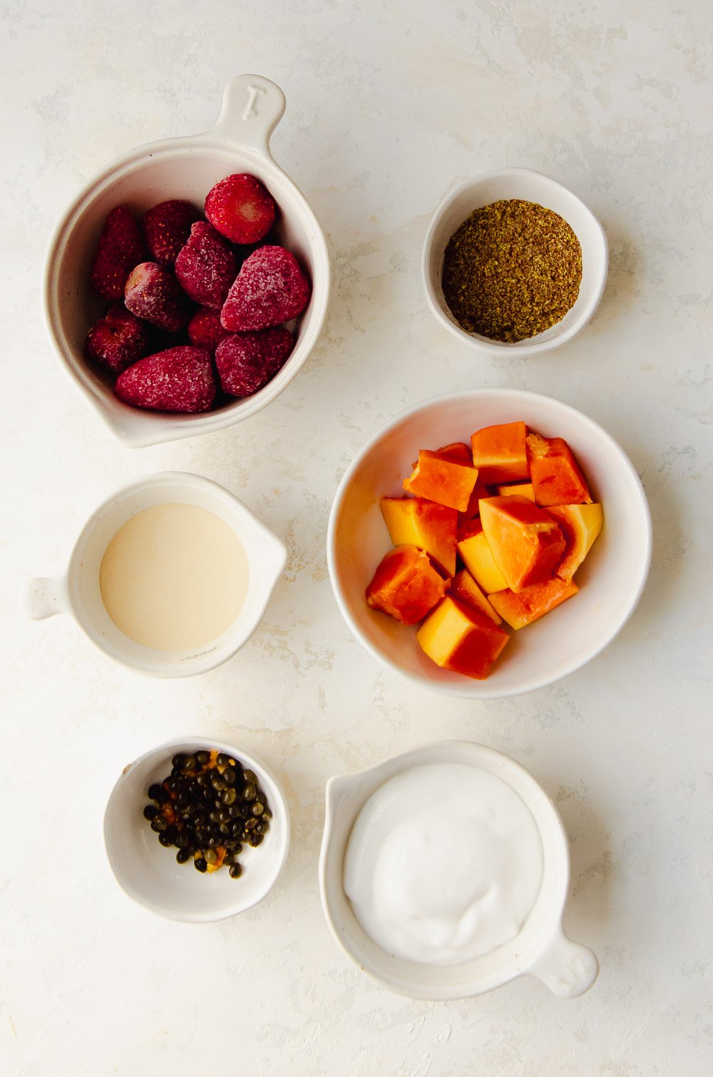 Six ingredients for this strawberry papaya smoothie include papaya, frozen strawberries, flaxseed, coconut yogurt, protein powder and papaya seeds.